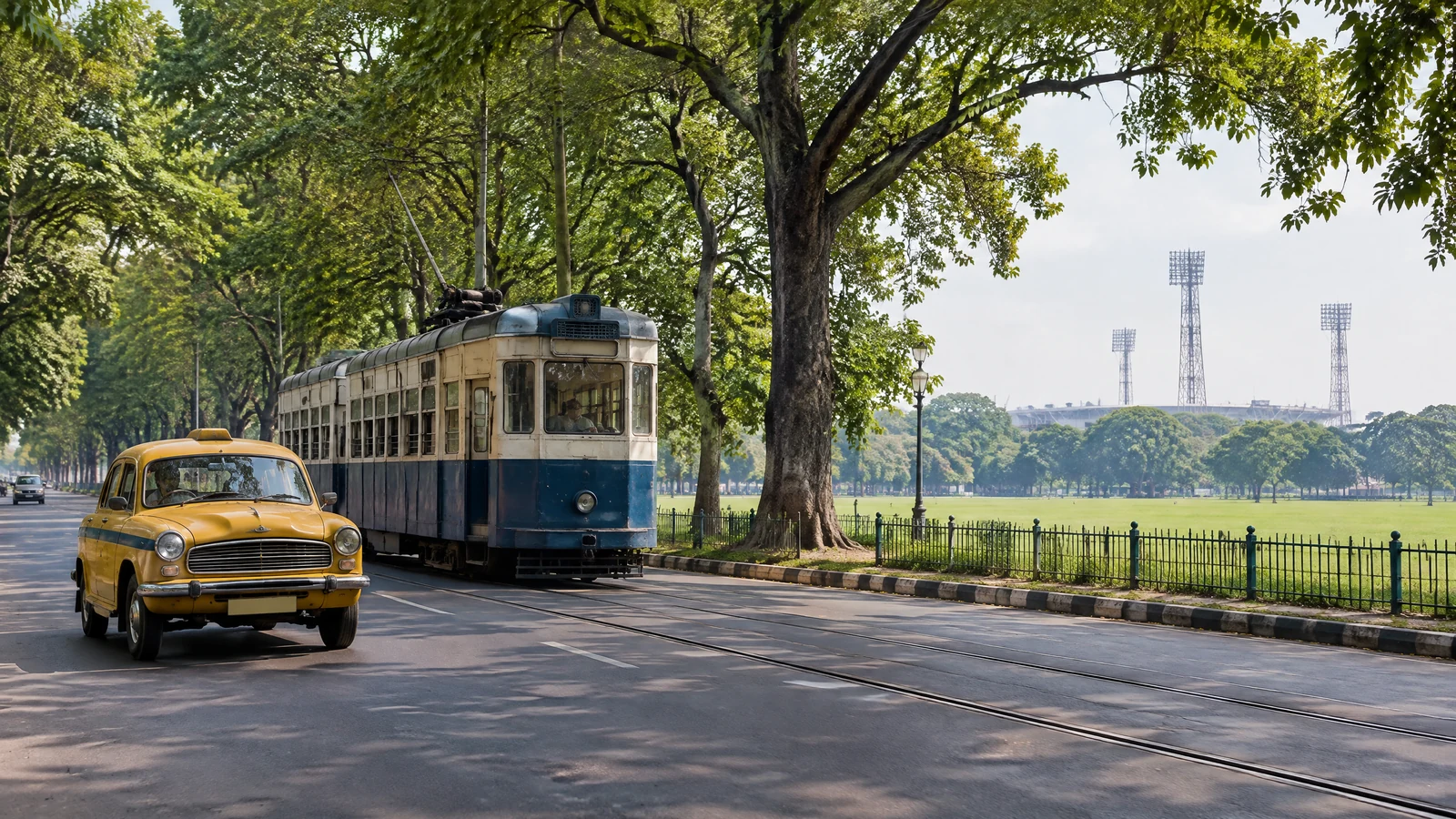 Yellow taxi on a tree-lined Kolkata road approaching Eden Gardens
